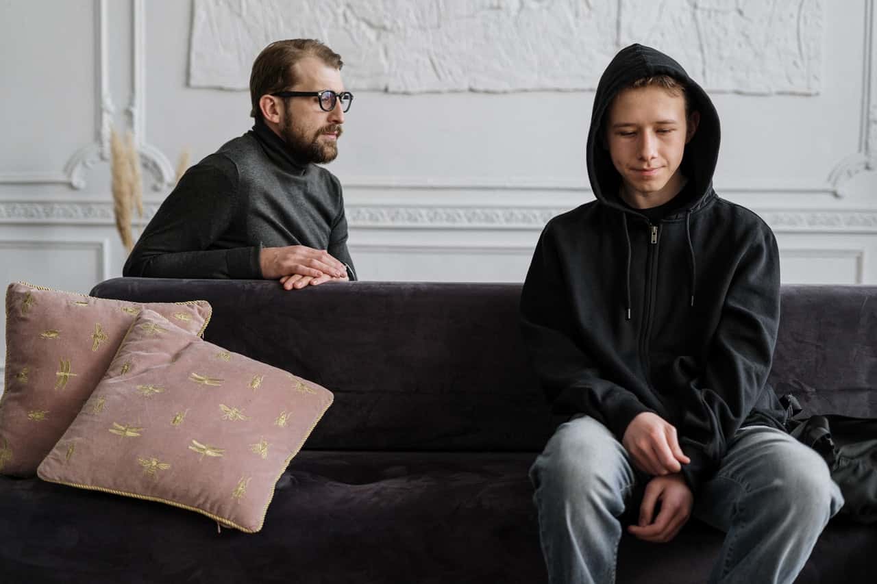 man-in-black-hoodie-sitting-on-brown-couch-4100428