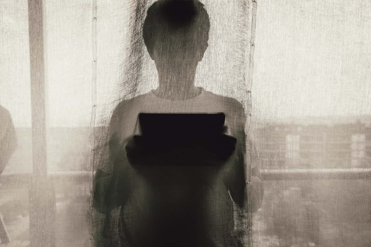 man-standing-holding-a-tablet-behind-curtain-1081675