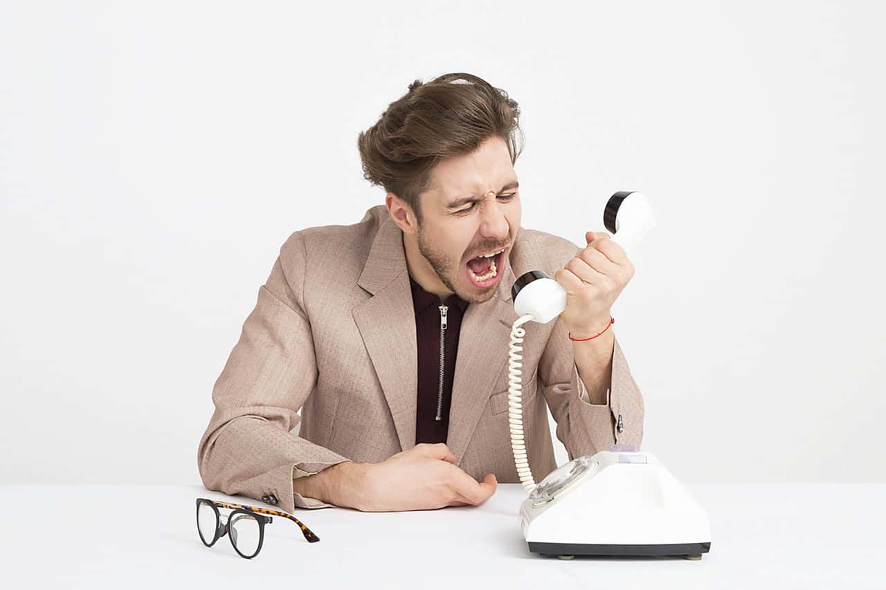man-wearing-brown-suit-jacket-mocking-on-white-telephone-1587014