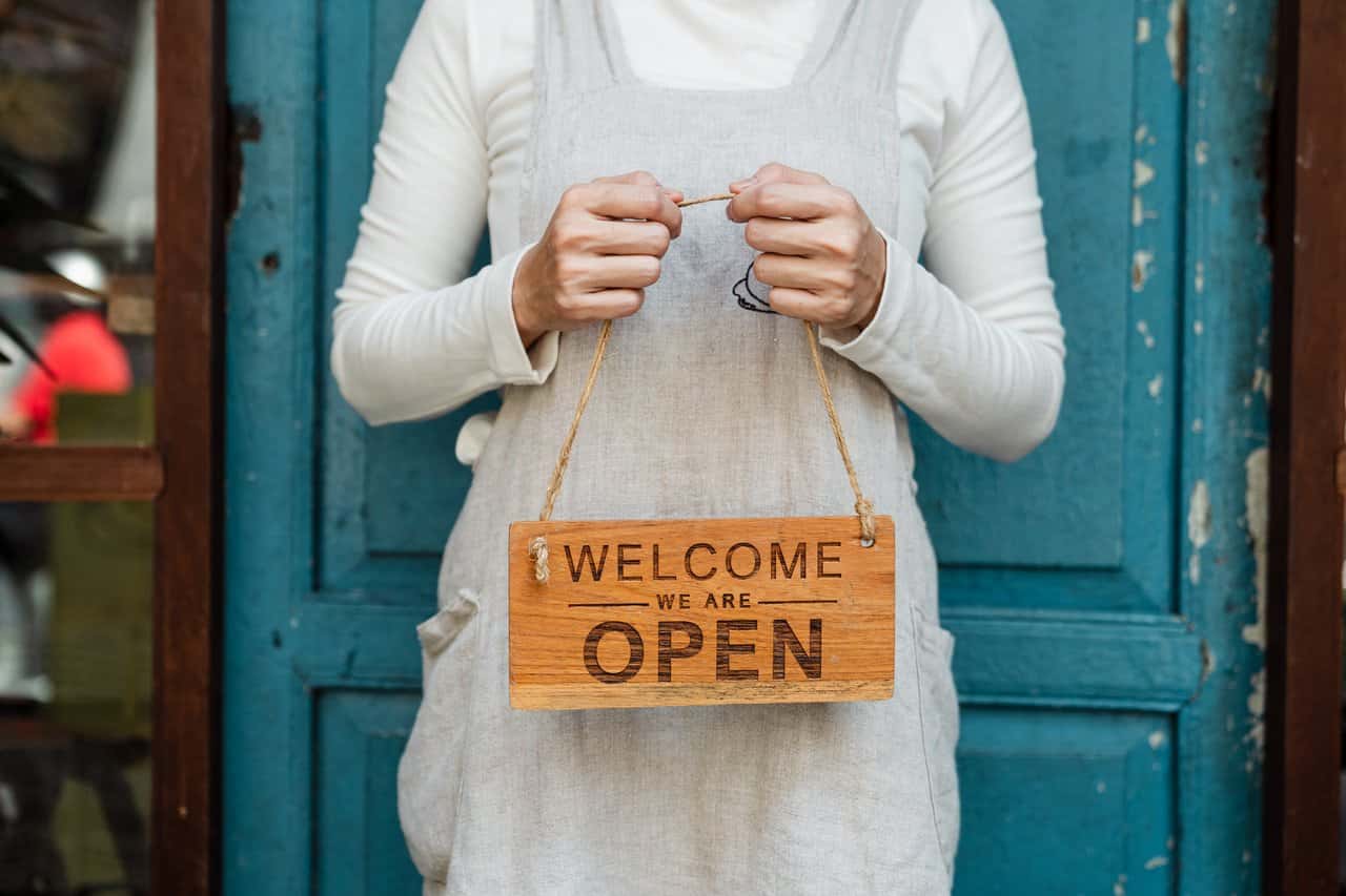 person-holding-brown-wooden-welcome-signage-4473357