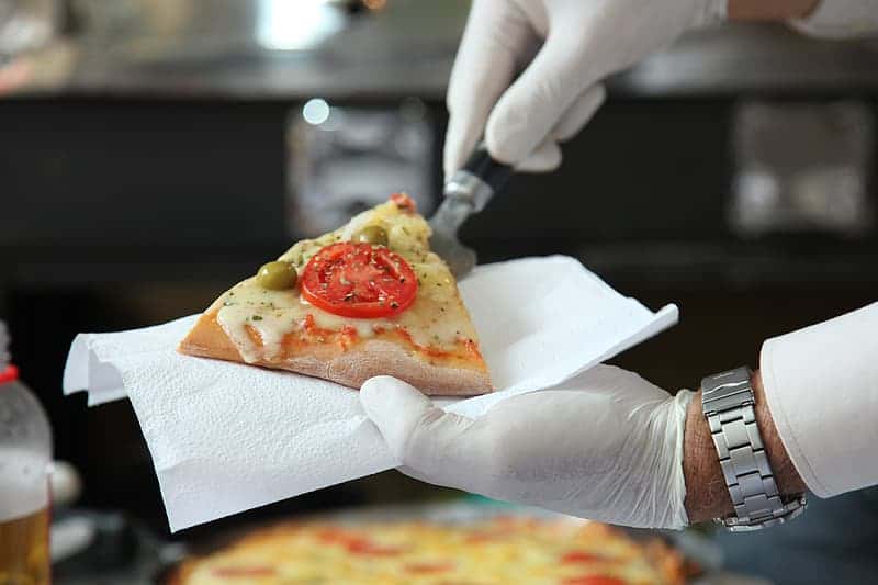 person-wearing-white-gloves-putting-a-slice-of-pizza-on-white-tissue