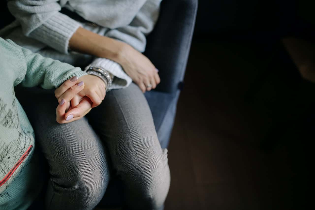 sitting-woman-in-gray-long-sleeved-shirt-holding-baby-s-hand-1684038