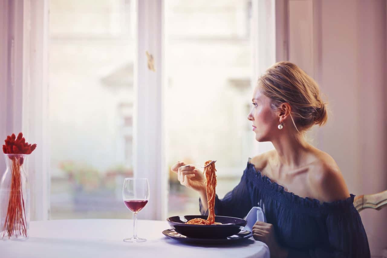 woman-sitting-on-chair-while-eating-pasta-dish-1456262