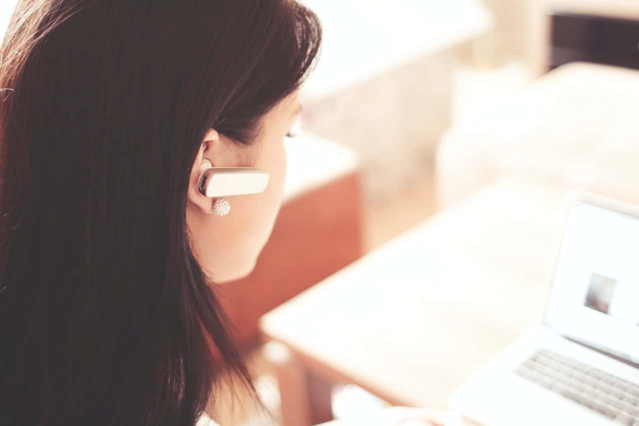 woman-wearing-earpiece-using-white-laptop-computer-210647