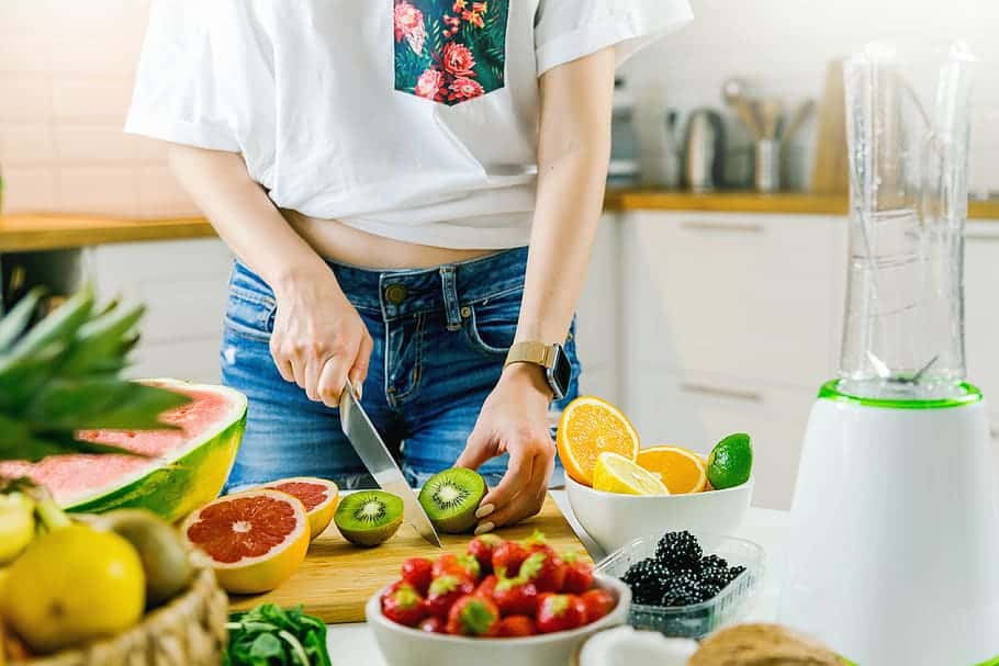 young-woman-cutting-fruits-healthy-smoothie