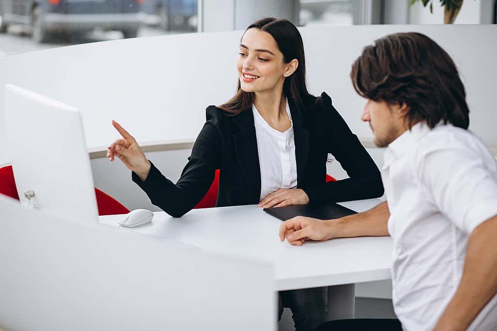 Man talking with female sales person in a car show room