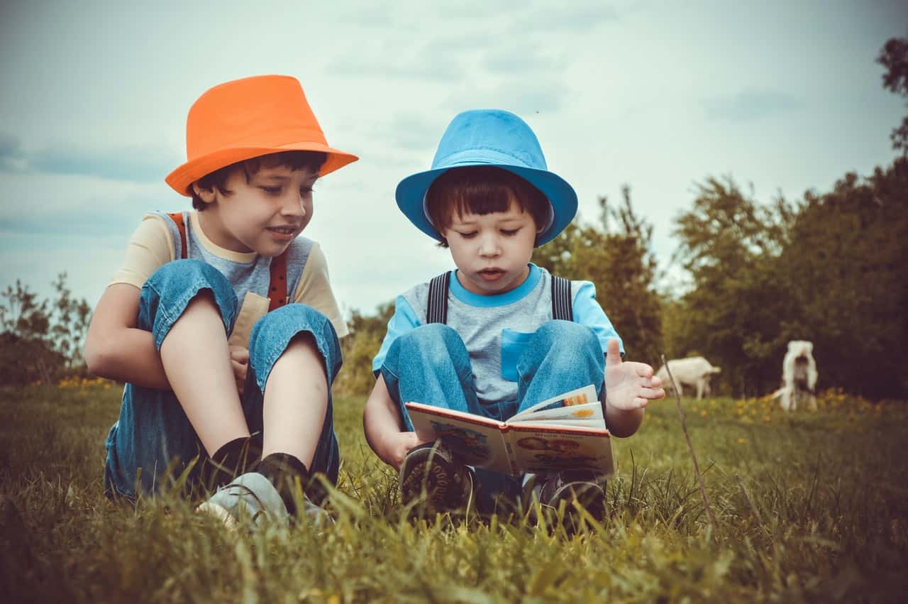 kids-sitting-on-green-grass-field-1094072
