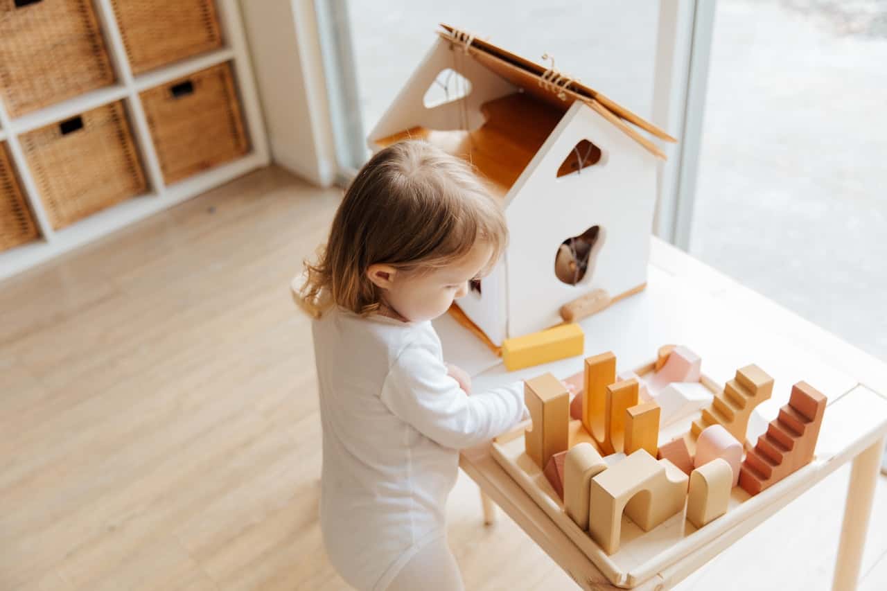 little-girl-playing-with-toys-at-table-near-window-at-home-3933043