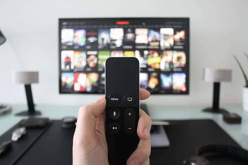 man-using-apple-television-with-remote-control-for-movies