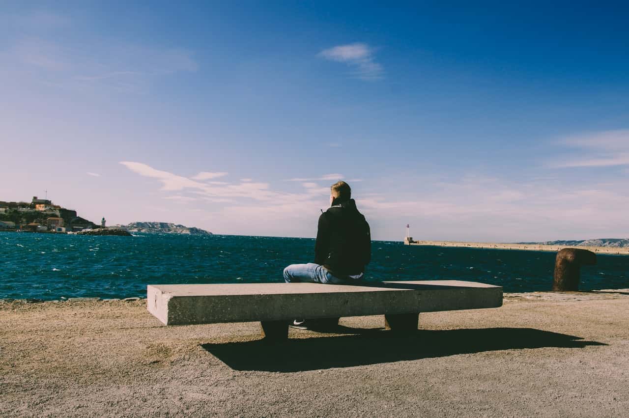 person-wearing-blue-jeans-sitting-on-bench-1074535