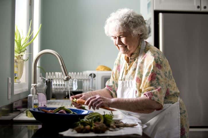 portrait-of-elderly-woman-in-kitchen-pictured-while-preparing-a-meal-725x483