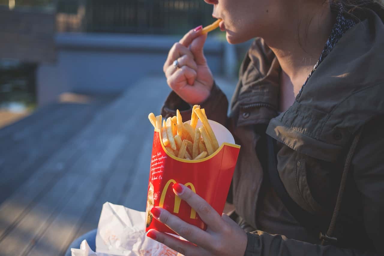 woman-in-brown-classic-trench-coat-eating-mcdo-fries-during-139681