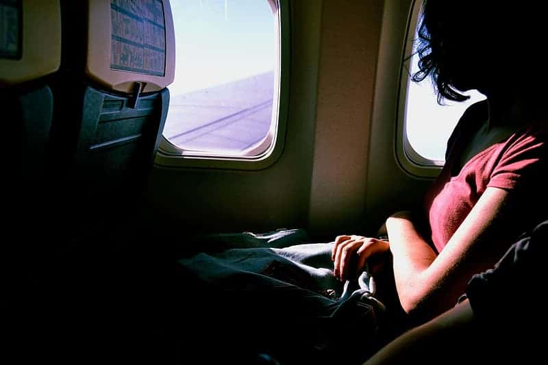 woman-wearing-red-t-shirt-inside-airplane-beside-window