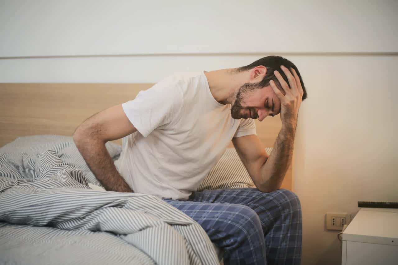 young-man-in-sleepwear-suffering-from-headache-in-morning-3771115