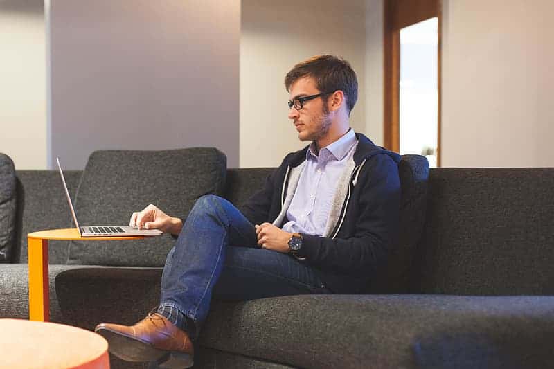man-in-black-zip-up-jacket-and-blue-denim-jeans-sitting-on-sofa