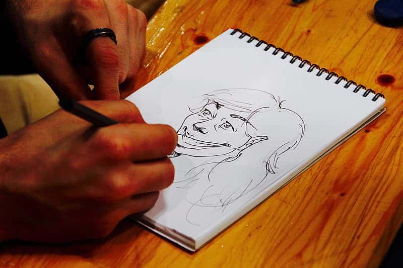 person-holding-pen-drawing-on-white-paper