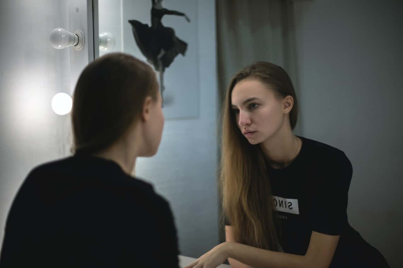 woman-in-black-shirt-facing-mirror-211024