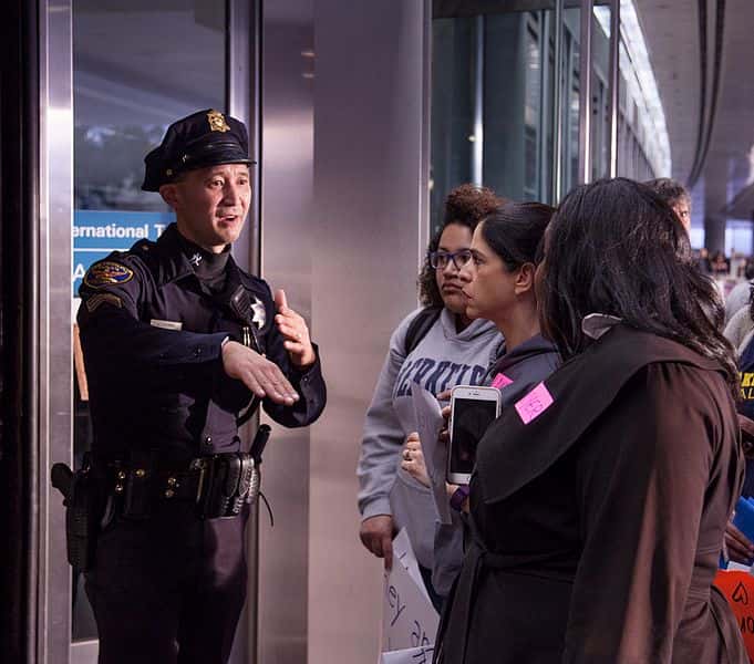 Lawyers_talking_to_SFPD_officer_at_SFO_-noban_Protest_-Jan_29,_2016_(31761490084)