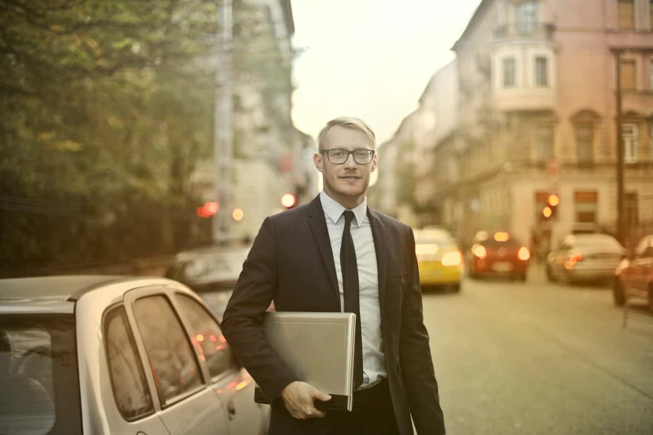 determined-smiling-businessman-with-laptop-on-street-3771089
