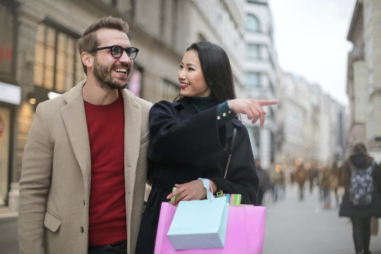 joyful-multiethnic-adult-couple-with-shopping-bags-walking-3775602