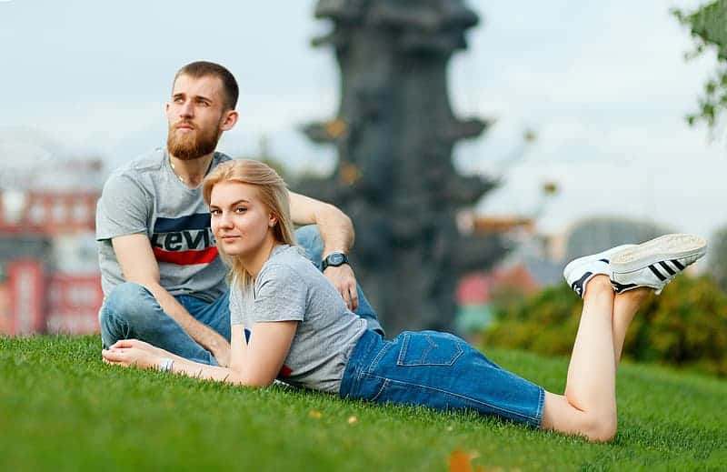 man-sitting-beside-woman-lying-on-grass-during-daytime