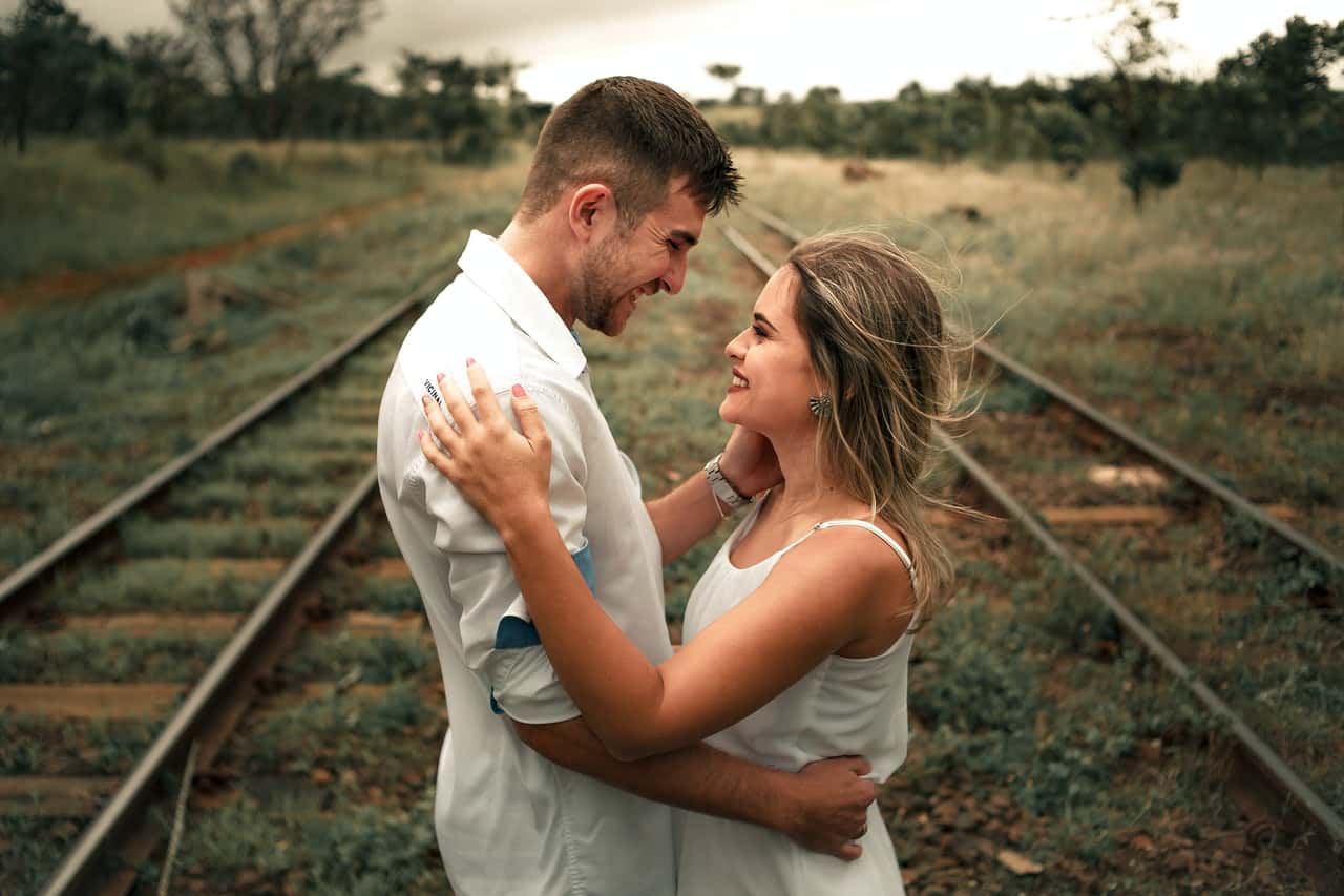 smiling-man-and-woman-facing-each-other-beside-railway-train-2983449