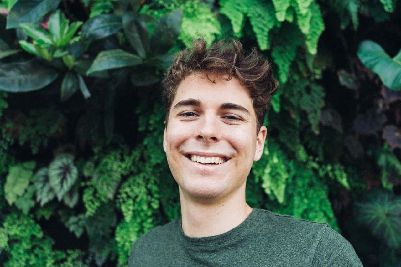 smiling-man-in-front-of-green-plants-2078265