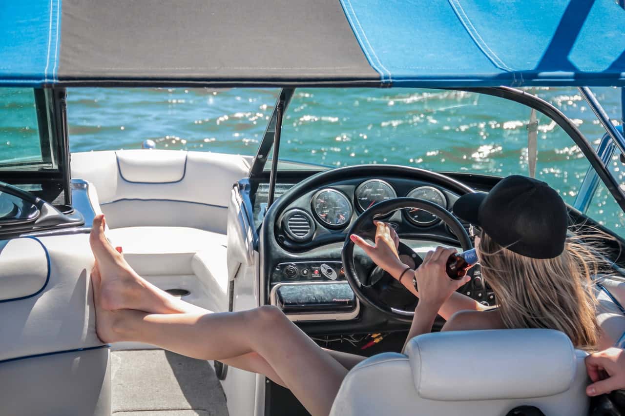 woman-wearing-black-cap-holding-bottle-on-white-speedboat-209978