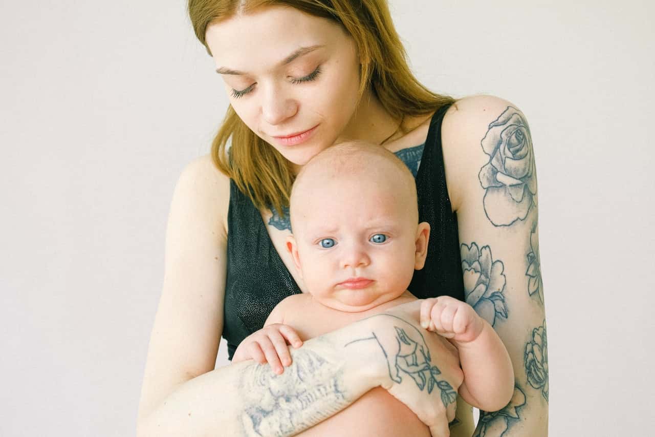 woman-with-tattoo-carrying-baby-3845171