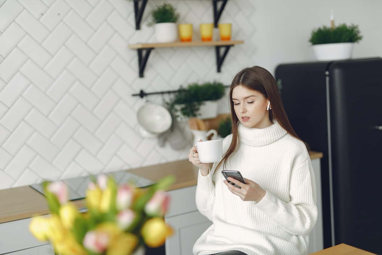 young-woman-with-smartphone-and-coffee-in-kitchen-4173309.jpg