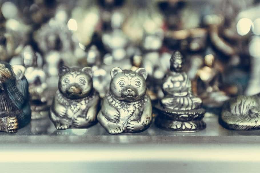 close-up-photography-of-silver-colored-bear-and-buddha-figurines