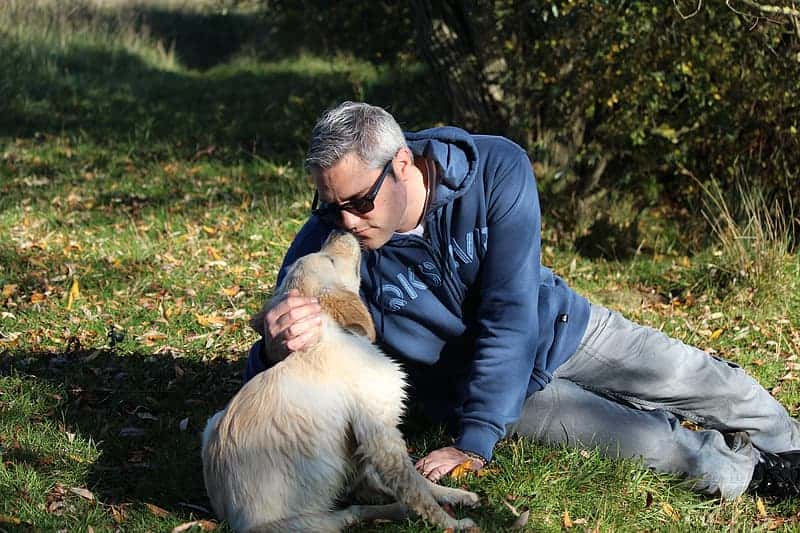 man-in-black-leather-jacket-hugging-brown-dog