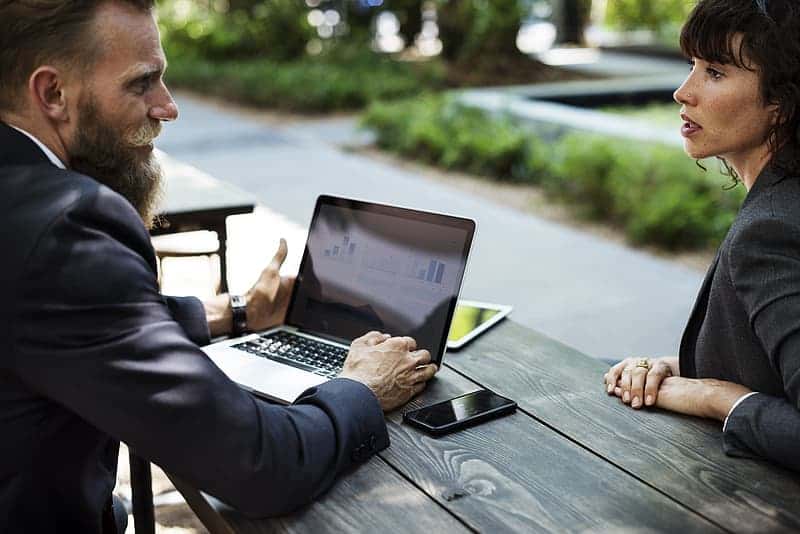man-and-woman-in-black-suit-sitting-in-front-of-table